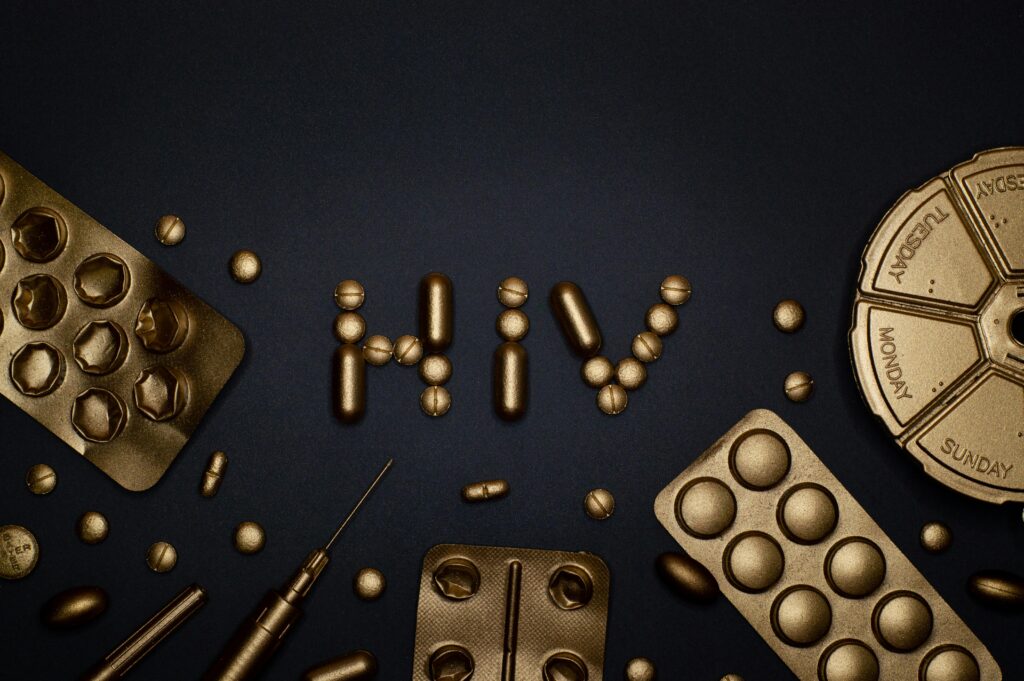 pexels-photo-3936368-3936368-2 Artistic depiction of HIV with golden pills and syringes on dark background.